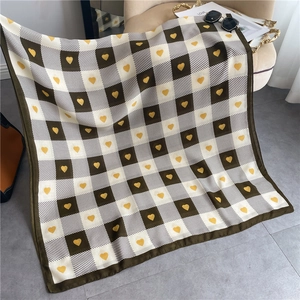Detail of checkered scarf with yellow heart pattern and soft fabric texture on a chair