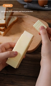 Manual butter spreader with protective lid shown being opened on a wooden bread board