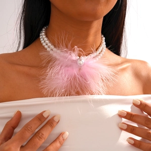 Close-up of double-layer pearl necklace featuring pink feather and baroque pearl detail