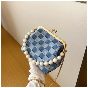 Detail of checkered woven bag with large faux pearl handle and gold clasp closure
