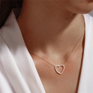 Minimalist s925 silver hollow heart necklace worn by a model on a white outfit