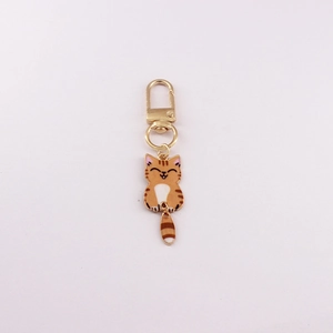 Close-up of golden cat keychain with orange enamel tabby design and movable tail