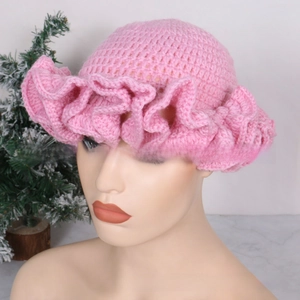 Close-up of pink handmade crochet sun hat with ruffled wavy brim on mannequin