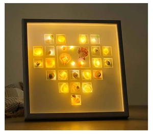 Close-up of heart-shaped natural seashell arrangement in a white lighted shadow box