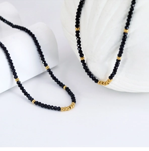 Detailed view of handmade beaded necklace with faceted black stones and small gold beads