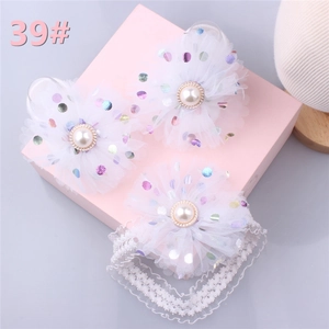 Close-up of baby headband and hair clips with white polka dot mesh flowers and pearls
