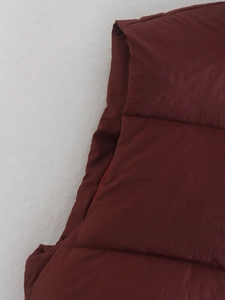 Detailed close-up of dark red quilted vest showing fine stitching and glossy fabric