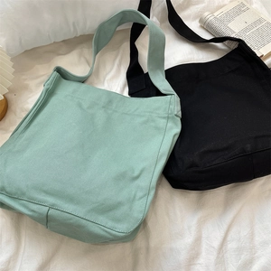 Dettaglio delle borse tote in tela verde chiaro e nera su uno sfondo bianco strutturato