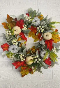 Close-up of autumn wreath with maple leaves, white berries and glitter pumpkins