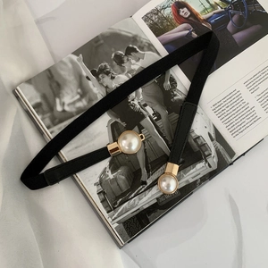 Detail of elegant black elastic belt featuring white pearls in gold ring settings