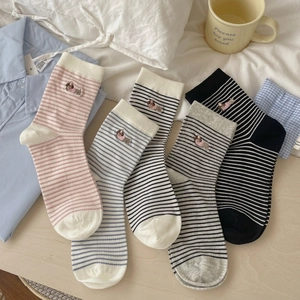 Five pairs of striped mid-calf socks with cute embroidery on a natural wood surface