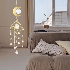 Acchiappasole luna dorata e cristallo appeso davanti a una finestra molto luminosa