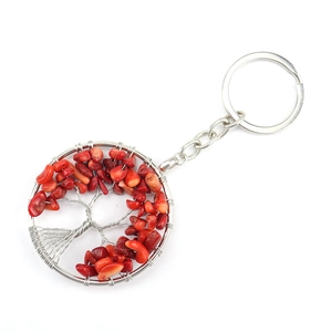 Detailed macro view of a silver Tree of Life keychain featuring red natural stone chips