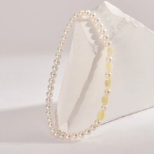 Close-up of white pearls and yellow oval beads displayed on white geometric plinths