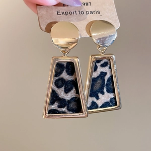 Macro shot of gold trapezoid earrings with leopard print fur inlays on display card