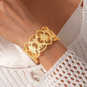 Macro shot of 18k gold-plated open cuff bracelet with hollow floral patterns and zircon