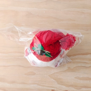 Detail view of a Christmas gnome plush toy in transparent packaging on wood background