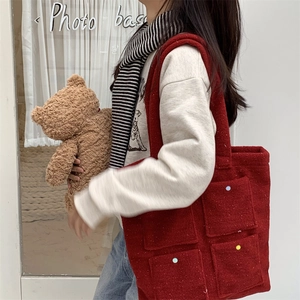 Red plush tote bag with multi-colored buttons and black-white scarf on model