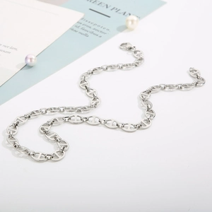 Detailed view of silver stainless steel pig nose anchor link necklace on a white table