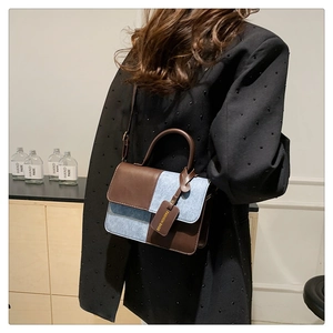 Detail showing blue denim and brown leather contrast handbag with round handle and strap