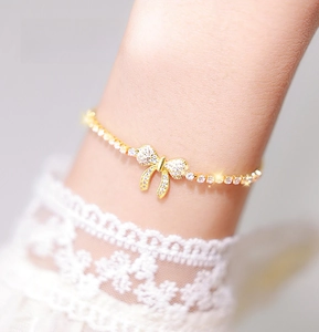 Close-up of sparkling cubic zirconia bow bracelet with golden claw chain detail
