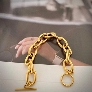 Detail of chunky gold chain bracelet with OT toggle clasp on a stylish magazine background