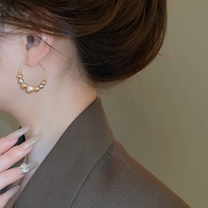 Detail of beaded hoop earring with large pearl and contrast metallic beads on model