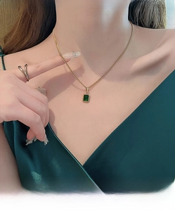 Macro detail of a vintage emerald pendant on a gold titanium steel necklace for women