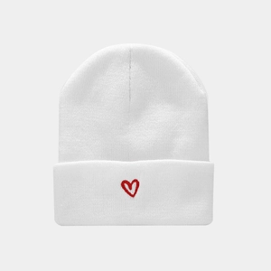 Close-up of white ribbed knit beanie featuring red heart embroidery on the folded cuff