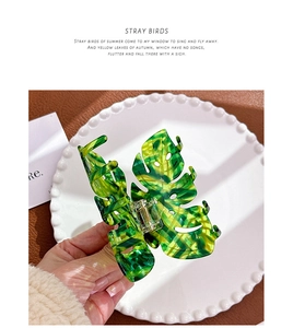 Macro detail of leaf-shaped hair claw clip with yellow and green marbled texture