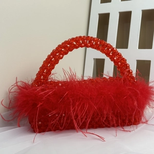 Detail of red beaded evening bag with fluffy ostrich feathers and woven handle
