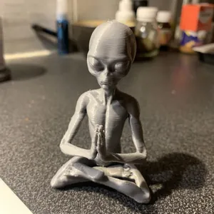 Close-up of a grey meditating alien resin figurine with visible 3D printed textures