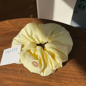 Detail of cream puff scrunchie with lace bow bead accessory on dark wood background