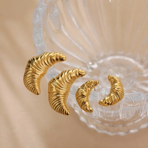 Set of four gold croissant hoop earrings in different sizes on glass rim