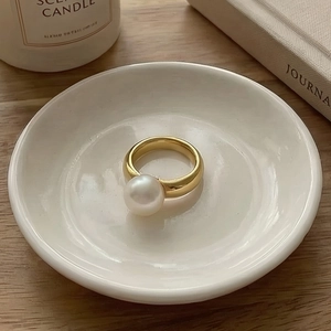 Minimalist gold stainless steel ring with a large white pearl in a lifestyle setting