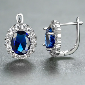 Macro shot of silver earring with oval blue sapphire and pavé-set white diamonds