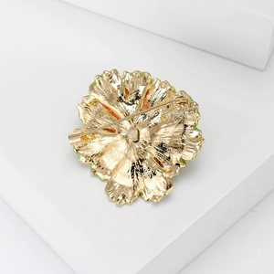 Back view of a gold flower brooch featuring a secure rotating pin lock and green enamel