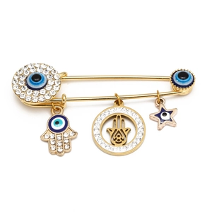 Detailed close-up of golden Evil Eye and Hamsa Hand charms on a rhinestone safety pin