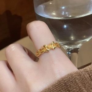 Close-up of elegant 24K gold plated bow ring worn on finger with soft water background