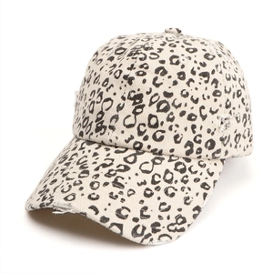 Close-up of distressed brim and leopard print texture on cream canvas baseball cap
