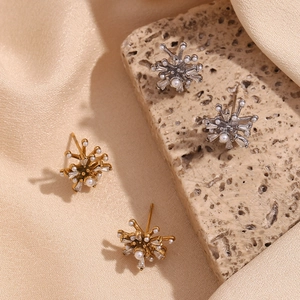 Detailed shot of starburst earrings with pearls and zircon on silk and stone background