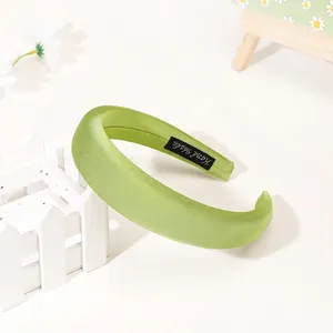 Detail of light green puffy satin headband showing the handmade label and soft silk texture
