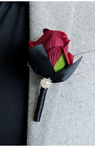 Detail of red rose boutonniere with black ribbon and pearl on a grey suit lapel