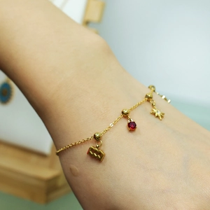 18K gold plated bracelet featuring a red gemstone star and wavy square charms on a model