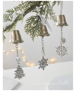 Silver and gold Christmas bells with snowflake pendants hanging on green branches