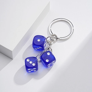 Macro detail of three blue translucent resin dice attached to a silver metal keychain