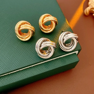 Détails des boucles d'oreilles nœud torsadé argent et or sur une boîte cadeau