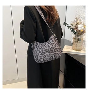 Rear view of model wearing leopard print crescent shoulder bag in grey and black tones