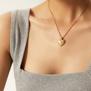Collier pendentif cœur doré élégant avec texture radiale et zircon sur un mannequin