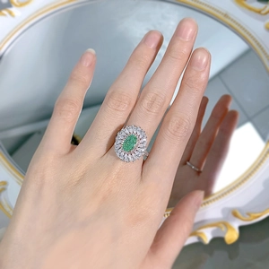 Detailed view of luxury oval green emerald-style ring with double halo diamond setting